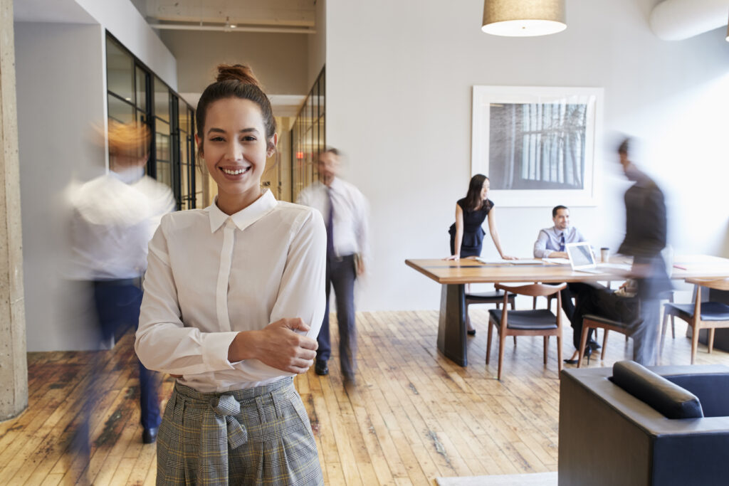 Portrait of young white woman in a busy modern workplace